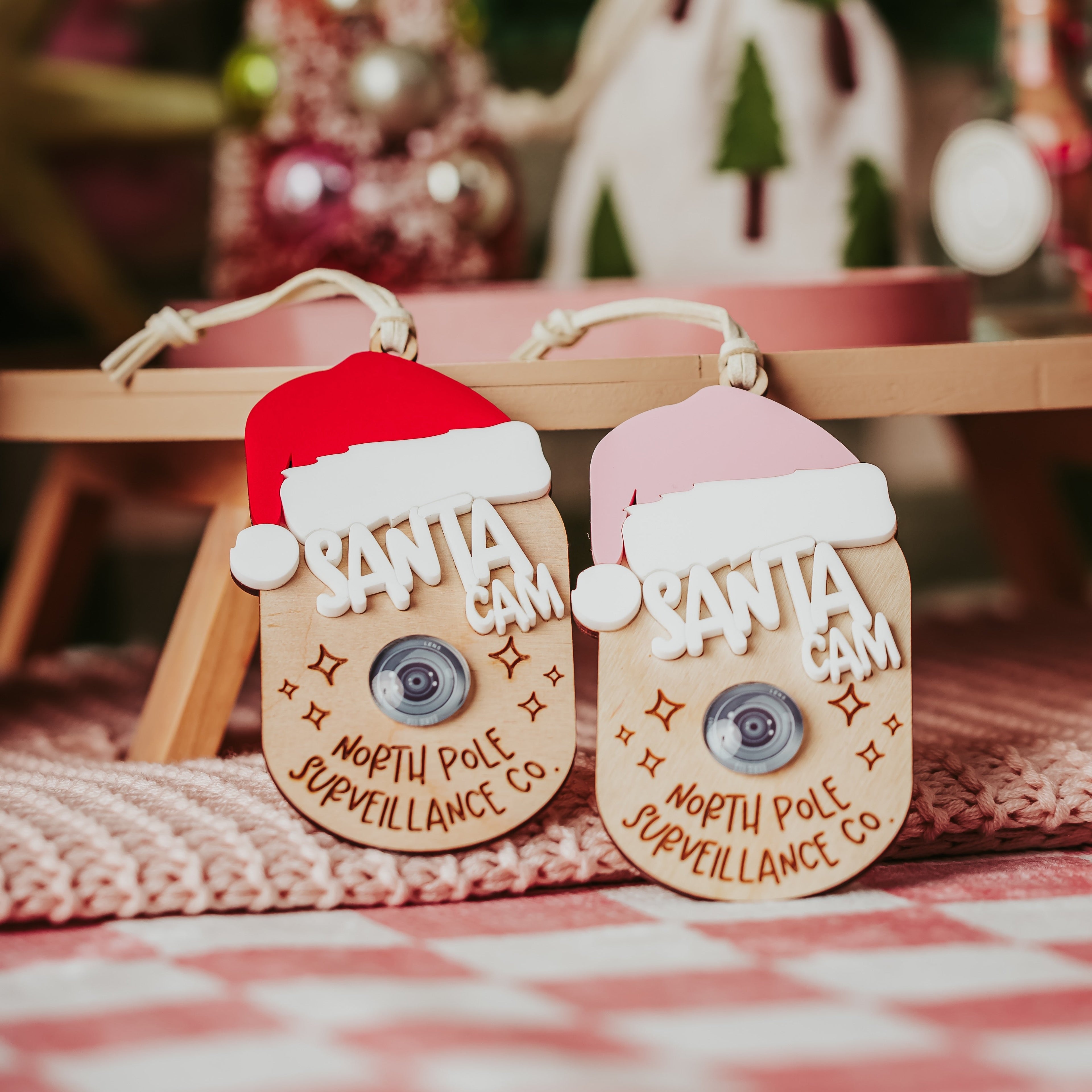 Two faux Santa Cam ornaments, one with a red Santa hat and the other with a pink Santa hat.